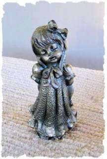  pewter figurine of a little girl day dreaming holding her hat behind