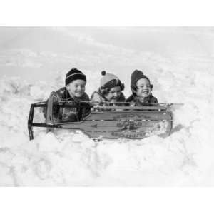  Two Girls and One Boy Lying on Belly in Snow Using Sled As 
